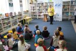 Zdjęcie przedstawia grupę dzieci i osobę dorosłą w Bibliotece.