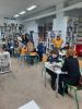 Zdjęcie przedstawia osoby grające w gry planszowe podczas cotygodniowych spotkań integracyjnych w Bibliotece.
