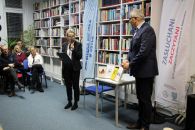 Zdjęcie przedstawiające Panią z mikrofonem przedstawiającą Pana