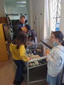 Zdjęcie przedstawia osoby oglądające wystawę starych monet, aparatów i dokumentów