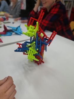 Zdjęcie przedstawia grających w grę planszową w bibliotece.