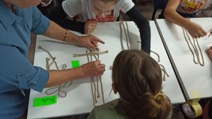 Zdjęcie przedstawia dzieci i młodzież podczas warsztatów makramowych