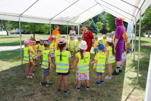 Dzieci i dorośli stoją w kręgu trzymając się za ręce w czasie gry sałatka owocowa