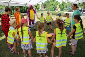 Dzieci i dorośli w przebraniach stoją w kółku trzymając się za ręce