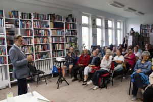 Zdjęcie przedstawia autora i publicznosc w czasie spotkania autorskiego
