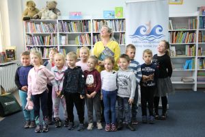 Zdjęcie przedstawia grupę dzieci i osobę dorosłą w Bibliotece.