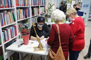 zdjęcie przedstawia kobiety w czasie wpisywania autografu do ksiazki