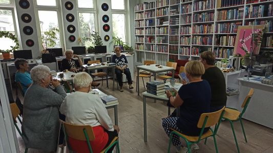 Zdjęcie Pan, siedzących przy stolikach w czasie spotkania dyskusyjnego klubu ksiazki