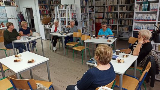 Zdjęcie Pan, siedzących przy stolikach w czasie spotkania dyskusyjnego klubu ksiazki
