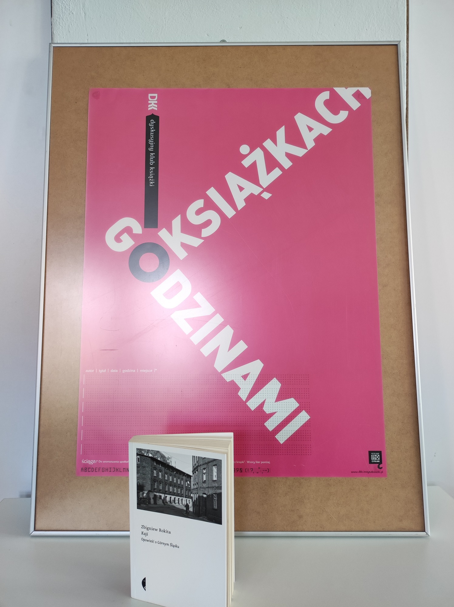 Zdjęcie przedstawia książkę i plakat