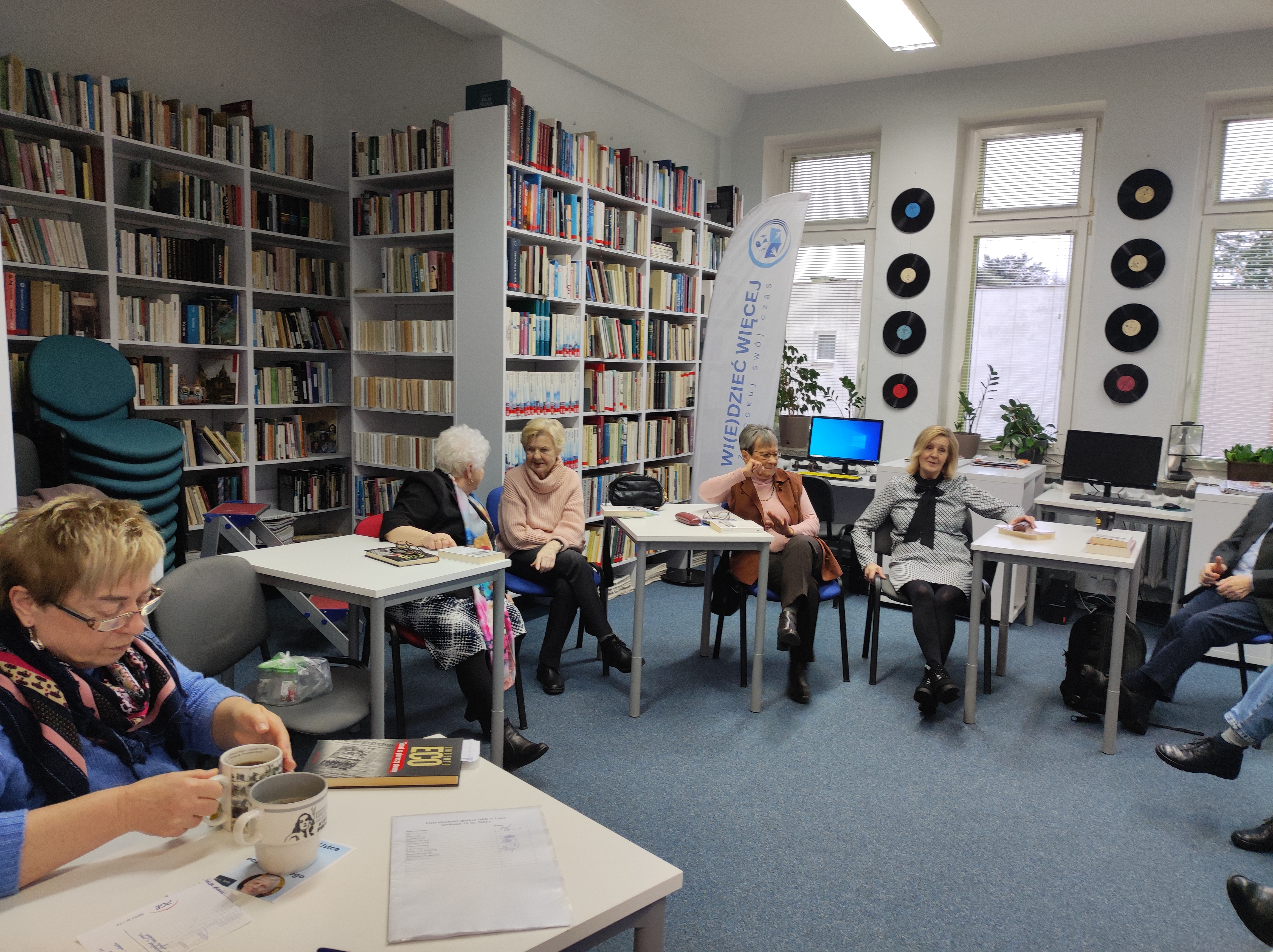 Zdjęcie przedstawia ludzi w bibliotece