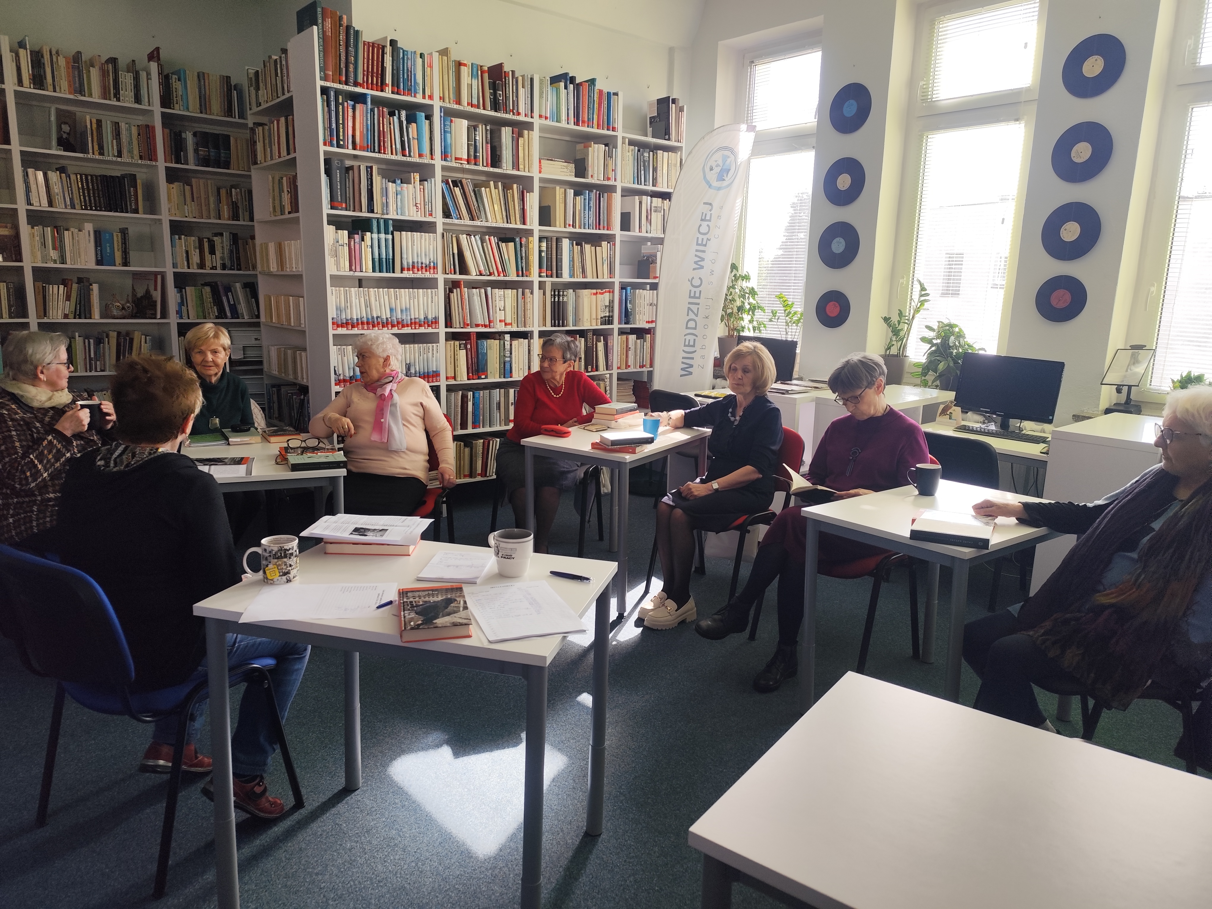 Zdjęcie przedstawia ludzi w bibliotece