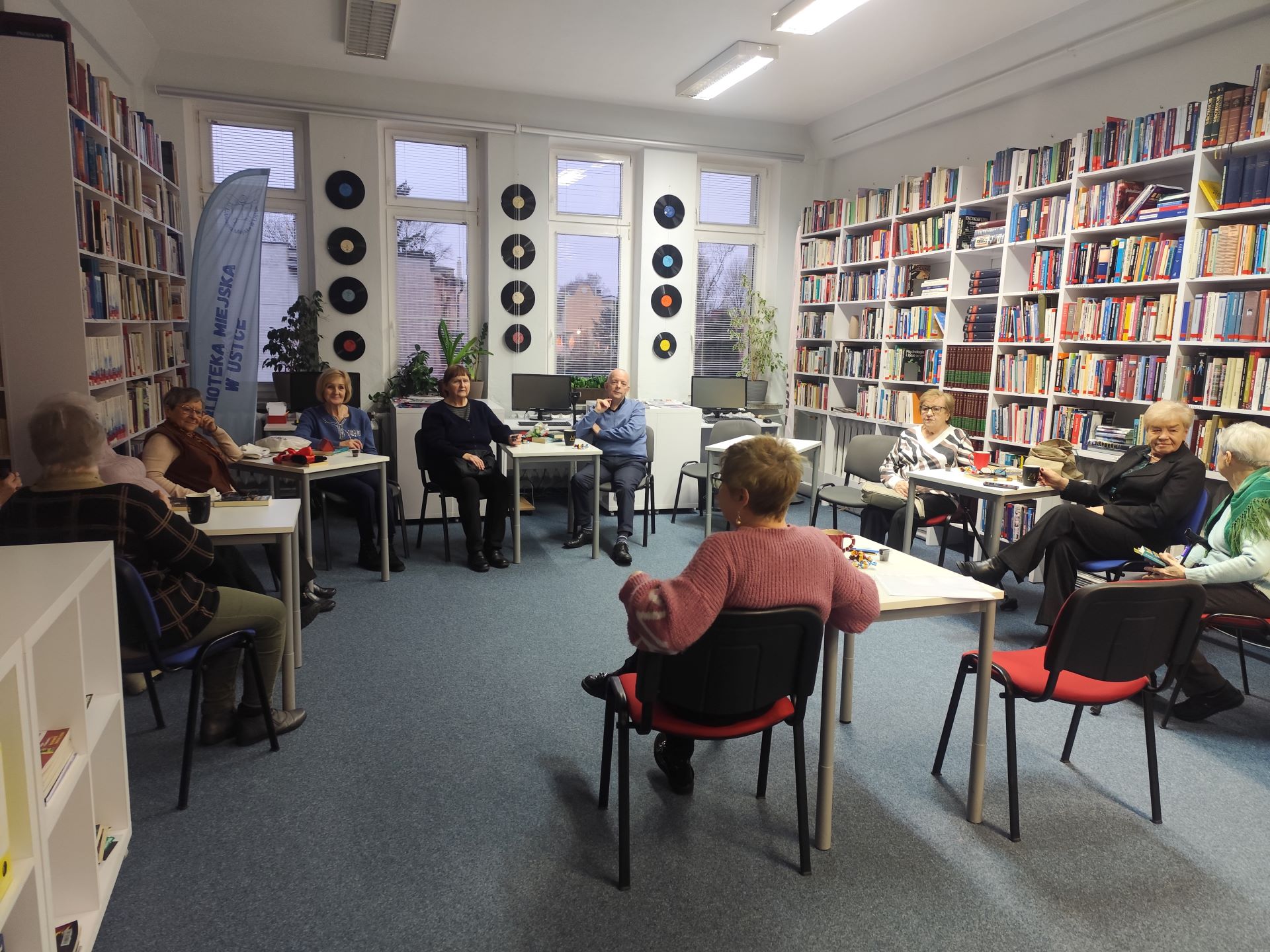 Zdjęcie przedstawia ludzi w bibliotece