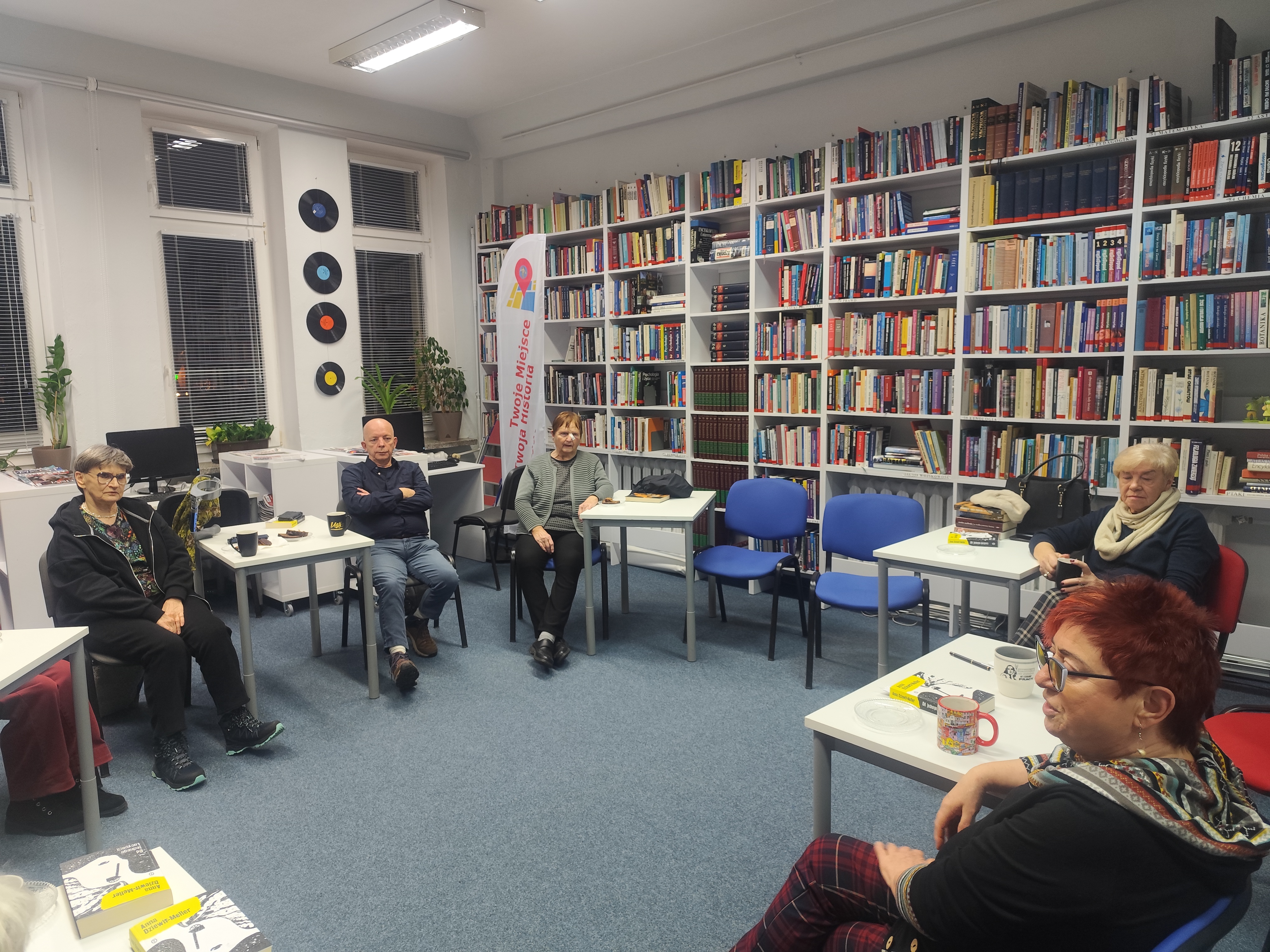 Zdjęcie przedstawia ludzi w bibliotece