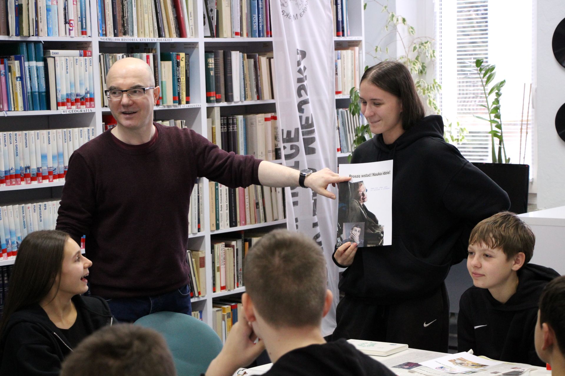 Zdjęcie przedstawia ludzi w bibliotece
