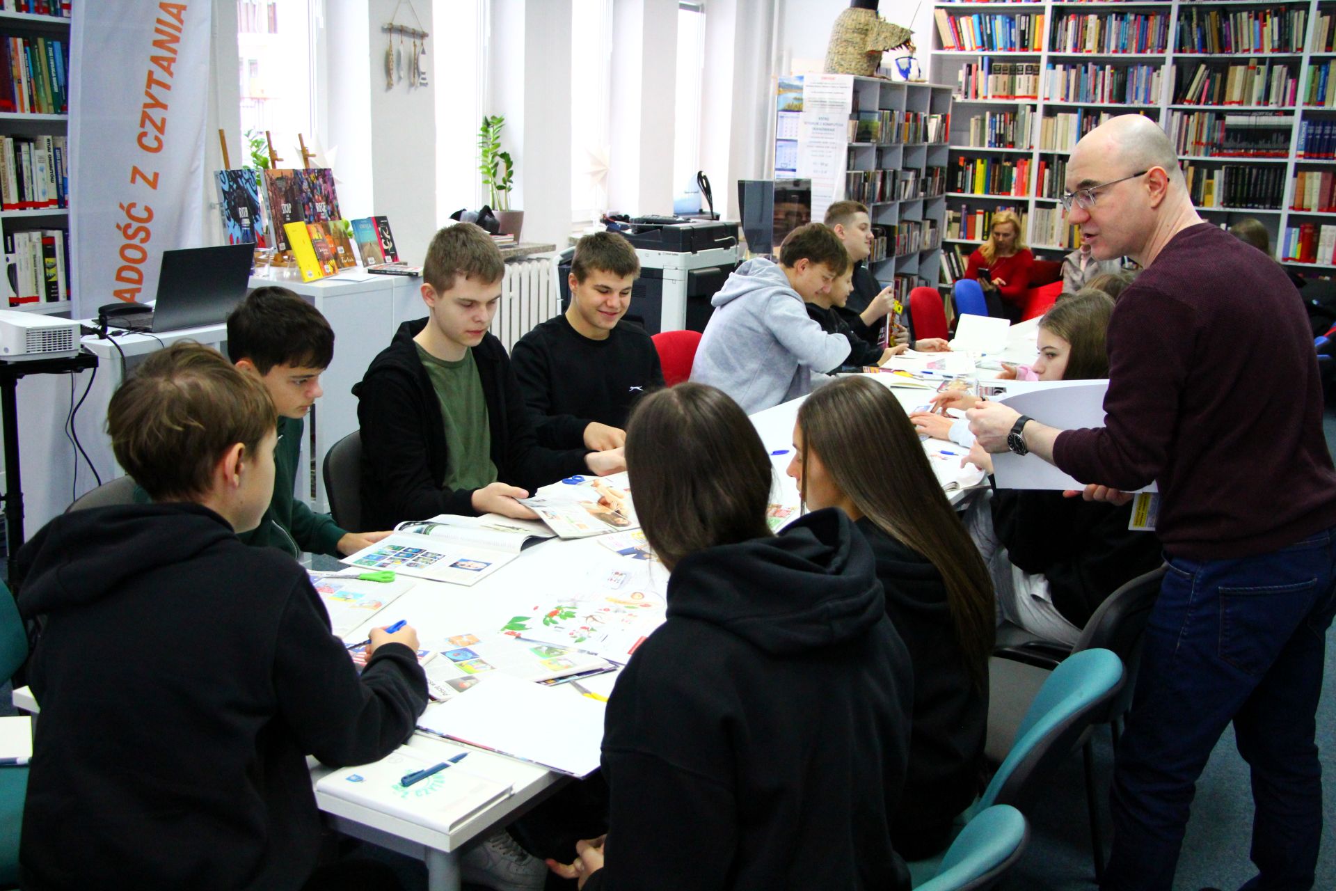 Zdjęcie przedstawia ludzi w bibliotece
